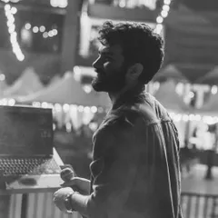 A side profile in black and white, with the stage lights creating a beautiful bokeh. A quiet moment before the next song.