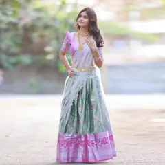 A beautiful half-saree in pastel shades of mint green and pink. This full-length outdoor shot showcases the entire outfit, including the intricate border and the elegant drape of the dupatta.