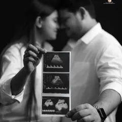 The first family photo. This black and white close-up shows the couple holding their baby's ultrasound scan, a deeply personal and emotional image that marks the beginning of their journey.