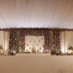 A wide shot of the entire indoor hall setup. The floral stage is the centerpiece, with the draped ceiling and elegant side decor creating a cohesive and grand look.