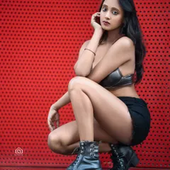 A dynamic crouching pose against the red wall, with the reflection on the floor adding another visual element. This shot is full of energy and modern style.