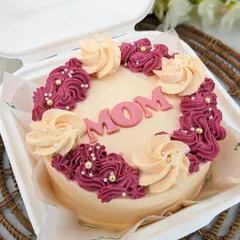 A close-up of our Mother's Day bento cake, beautifully decorated with pink and cream frosting and the word "MOM" in the center.