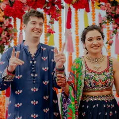 Pure happiness and victory signs from the happy couple during their Mehendi ceremony. Their vibrant, colorful outfits perfectly match the joyous mood of the event.