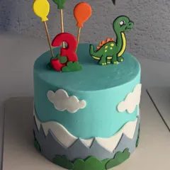A close-up of one of the twin dinosaur cakes, showing the cute fondant dino and balloon toppers.