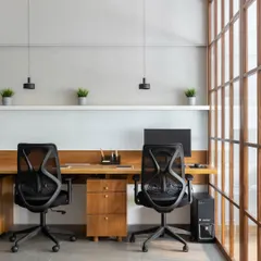 A shared workstation area designed with simplicity and function in mind. The long wooden desk, minimal pendant lights, and ergonomic chairs create a clean and productive workspace.