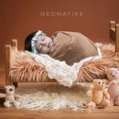 Tucked in and cozy. A sleeping newborn on a tiny wooden bed, surrounded by teddy bears. This is a classic and heartwarming setup.