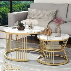 This contemporary nesting table set features a larger C-shaped table and a smaller round table, both with gold-finish wireframe bases. The white marble-finish tops provide a clean, luxurious look for modern living rooms.