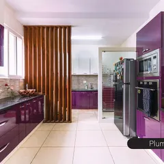 This kitchen makes a bold statement with glossy, plum-purple cabinets. The design includes a dedicated utility area separated by a wooden screen, maximizing space and organization in a stylish way.