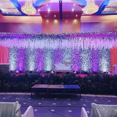 For a more elegant and formal conference, I created this beautiful stage using a curtain of white flowers. The purple uplighting added a touch of brand color and sophistication, transforming a simple hall into a professional and inviting space.