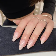 A beautiful set of long, stiletto-shaped nails with a natural, sheer pink gel polish. This look is both modern and sophisticated, showcasing healthy nails and expert shaping.