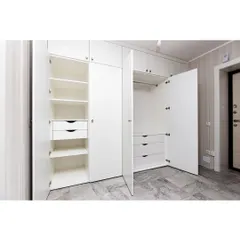 A floor-to-ceiling white wardrobe with ample storage, including drawers and hanging space. The clean, minimalist design helps to make the room feel larger and more organized.