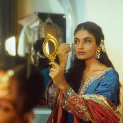 A storytelling moment from a campaign shoot. The model applying makeup in a vintage mirror creates a narrative of preparation and quiet beauty.