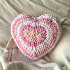 Our crochet heart pillow, made with concentric rings of pink and white, is perfect for adding a touch of handmade charm to your bed or couch. It's soft, squishy, and made with love.