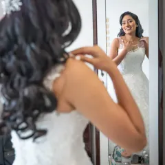 A happy moment of reflection. The bride catches her own smiling face in the mirror as she gets ready, a perfect candid shot of her excitement.