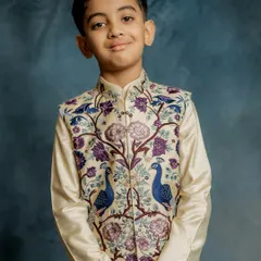 A portrait of pure elegance. This young model wears our peacock-embroidered Bundi jacket, a piece that combines traditional motifs with exquisite craftsmanship for a truly regal look.