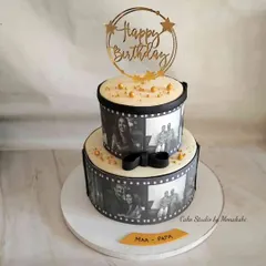 A beautiful monochrome two-tier cake for a combined parents' birthday. The edible photo reels wrap around each tier, showcasing cherished family moments in a classic black and white style.