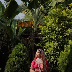 A bride stands amidst lush greenery, the natural light highlighting her vibrant pink lehenga. This portrait showcases our ability to use natural environments to create stunning bridal shots.