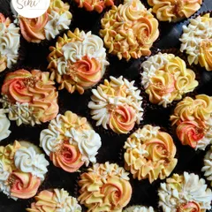 These pineapple-flavored cupcakes are decorated with two-toned buttercream swirls in sunset shades of orange and yellow, with a sprinkle of gold for a tropical feel.