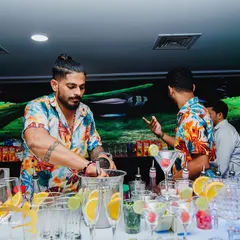 A bartender in his element, muddling fresh ingredients for a cocktail. This action shot captures the hands-on craft and attention to detail that goes into every drink we make.