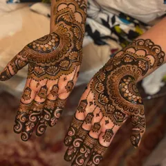 This design features beautiful hanging "jhumka" or earring motifs, a popular element in Gulf-style henna, combined with a large mandala.