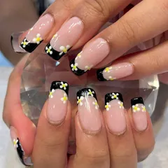 A Pinterest-inspired design brought to life. This creative take on a French manicure features a black tip adorned with sweet, hand-painted daisies.