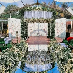This stunning mandap features a mirrored aisle that reflects the entire structure, creating a spectacular visual. The setup, under a clear tent, combines natural elements with modern design for a truly unique wedding.