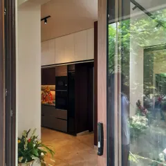 This elegant kitchen overlooks a canopy of greenery, blurring the line between indoors and out. We used a subtle palette of white and grey solid colors, which marry beautifully with the luxurious wood and marble flooring for a sophisticated look.