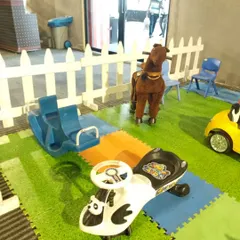 A variety of ride-on toys, including a rocking horse and a push car, set up on a soft play mat. I offer a range of toys to suit different toddler interests.