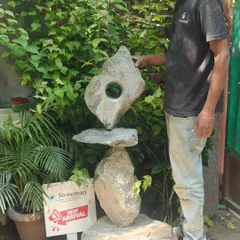An artisan stands beside the 4-foot "Balance of Life" sculpture, providing a sense of its scale. This piece is crafted to be a striking focal point in any modern garden.