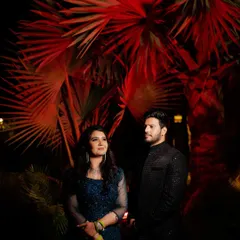 A dramatic night portrait using creative lighting to make the red palm leaves pop. This is how we turn a simple background into a stunning, artistic element for a sangeet night photo.