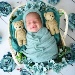 A sleepy smile that will make your heart melt. This little one is snuggled between two crocheted teddy bears, wrapped in a soft teal knit.