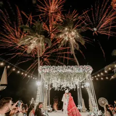 A destination wedding dream. The varmala on a beach stage, with palm trees and fireworks lighting up the night sky, is the definition of an epic celebration.