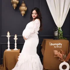 A beautiful solo portrait of a mom-to-be in a white lace mermaid gown. The dark, moody backdrop with Moroccan-style lanterns creates a sophisticated and elegant atmosphere.