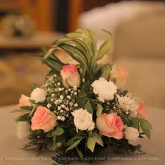 A classic and elegant floral centerpiece composed of blush pink roses, white carnations, and delicate baby's breath. This timeless arrangement adds a touch of grace and sophistication to any guest table or lounge area.