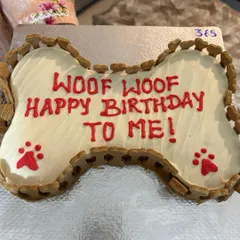 A close-up of my popular bone-shaped dog cake. It's framed with my signature handcrafted biscuits and features personalized writing, making it a centerpiece for any dog's party.
