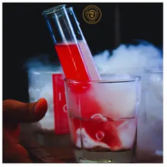 A signature molecular cocktail. The vibrant red liquid from the test tube mixes with the smoky base, creating an enchanting visual and a unique flavor experience.