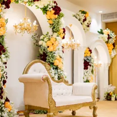 A close-up of the intricate floral work and classic seating from one of our Vashi wedding projects. The combination of a vintage-style chaise lounge with vibrant flower arrangements creates a picture-perfect setting.