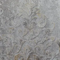 A close-up of a regal Indian-inspired wallpaper. The detailed damask pattern on a textured grey background exudes a sense of timeless luxury, perfect for creating a statement wall with historical charm.