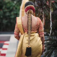The back of a bride is just as important as the front. This image showcases a classic South Indian bridal braid, complete with a 'Jadai Billai' and flowers, against a beautiful gold and red Kanjivaram saree.