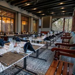 Another perspective of the outdoor dining space at Ebony, highlighting the custom metal and marble tables and the intricate screen work.