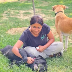 We care for your fur babies as if they were our own. Here, Asha gives a relaxing belly rub to a black dog enjoying the grass. We manage everything from specialized diets to medication, ensuring expert care that only fellow dog parents can provide.