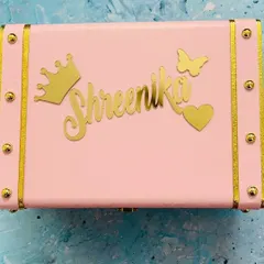 Shown here in a soft pink, this personalized trunk box is a popular choice for gifting. The combination of the name, crown, butterfly, and heart charms creates a truly charming piece.