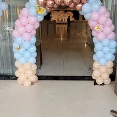 A beautiful balloon arch in pastel pink, blue, and peach with gold butterfly accents, creating an inviting entrance for the butterfly-themed party.