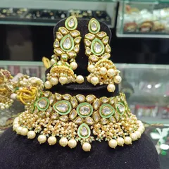 A lovely pastel green meenakari choker set that is very popular for day functions. The large kundan stones are set beautifully with pearls, and the matching jhumkas make it a very elegant choice.