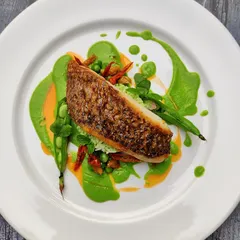 An example of our main course artistry: pan-seared fish with a vibrant green pea purée, showcasing our focus on fresh ingredients and beautiful presentation.