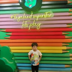 A little boy stands proudly in front of our "Tingaland Superstar" neon sign and colorful pencil wall.