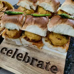 Celebrate with a platter of our mini Vada Pavs. Soft pav buns are layered with spicy garlic chutney and a hot potato vada, garnished with a fried green chilli for that extra kick.