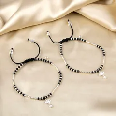 A pair of Nazariya-style anklets or bracelets with black beads and a silver diamond-shaped charm.