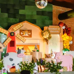 The full view of the barnyard stage, complete with a windmill, a friendly cow, and a happy pig. The lighting and green backdrop create a warm and rustic atmosphere inside the venue.