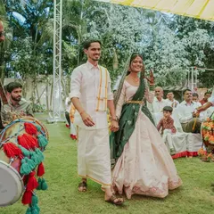 The couple makes their grand entrance to the haldi ceremony, accompanied by dhol players. This shot captures the festive energy and traditional start to the event.